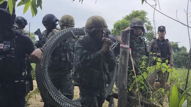 Foto yang dirilis oleh Agence Kampuchea Press (AKP) menunjukkan tentara Thailand membawa kawat berduri di Desa Prey Chan, di sepanjang perbatasan yang disengketakan dengan Kamboja, Rabu (17/9/2025).