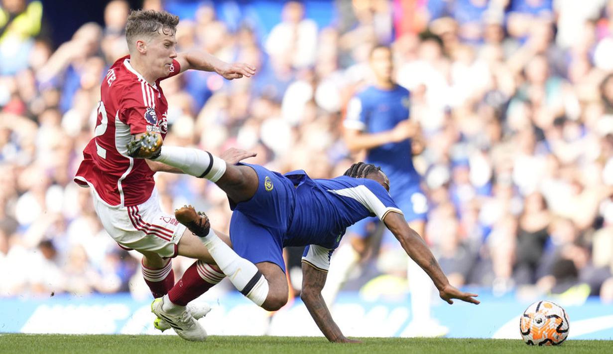 Pemain Chelsea, Raheem Sterling, terjatuh saat berebut bola dengan pemain Nottingham Forest, Ryan Yates, pada pertandingan pekan keempat Premier League 2023/2024 di Stadion Stamford Bridge, Sabtu (2/9/2023). Chelsea takluk 0-1 dari sang tamu. (AP Photo/Kirsty Wigglesworth)