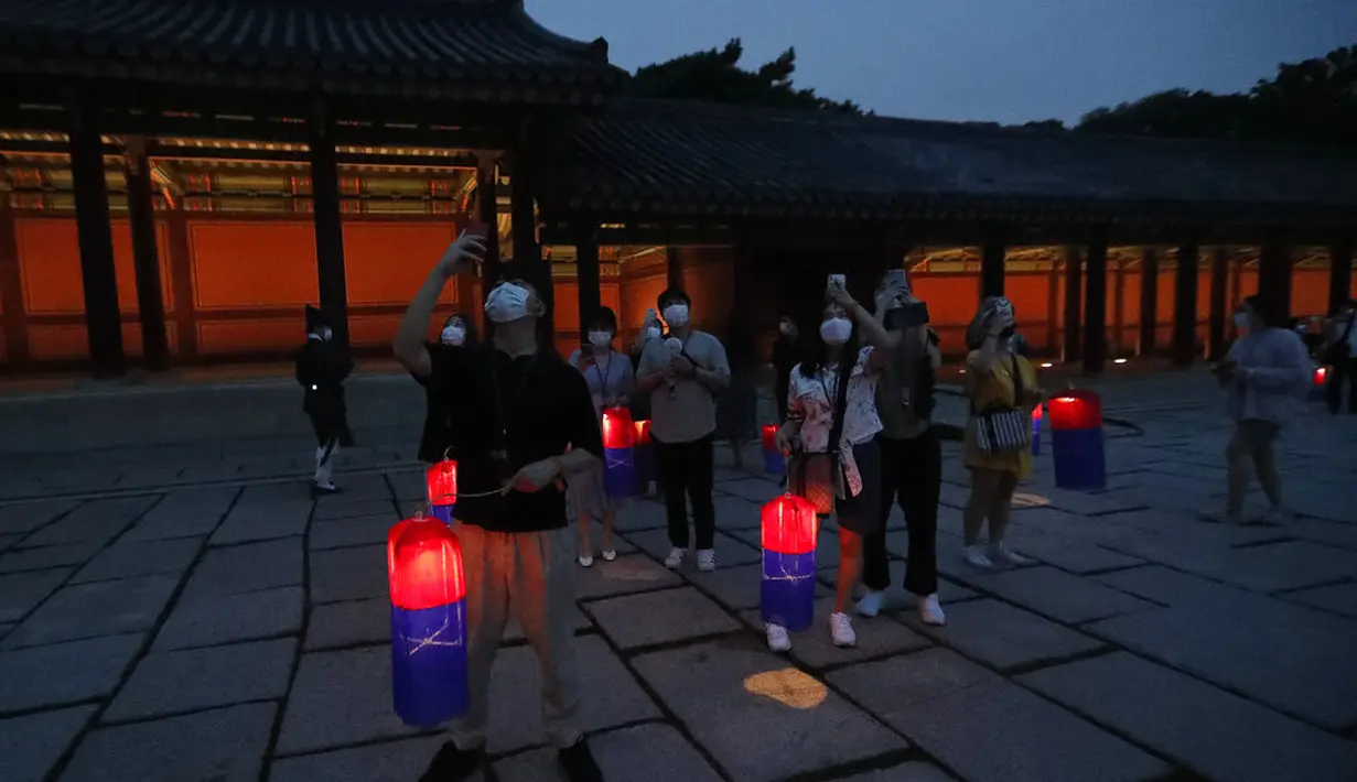 Pengunjung memegang lentera tradisional Korea berjalan-jalan selama Tur Cahaya Bulan di Istana Changdeokgung di Seoul, Korea Selatan, Kamis, (13/8/2020). Istana dibuka kembali pada Kamis setelah ditutup selama dua bulan karena pandemi Covid-19. (AP Photo/Ahn Young-joon)