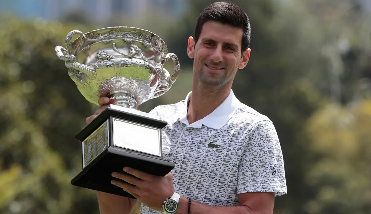 Petenis Serbia, Novak Djokovic berpose dengan piala juara tunggal putra Australia Terbuka 2020 saat sesi pemotretan di Royal Botanic Gardens Victoria, Melbourne, Australia, Senin (3/2/2020). Djokovic sudah mengoleksi sebanyak 17 gelar grand slam dengan kemenangan kali ini. (AP Photo/Dita Alangkara)