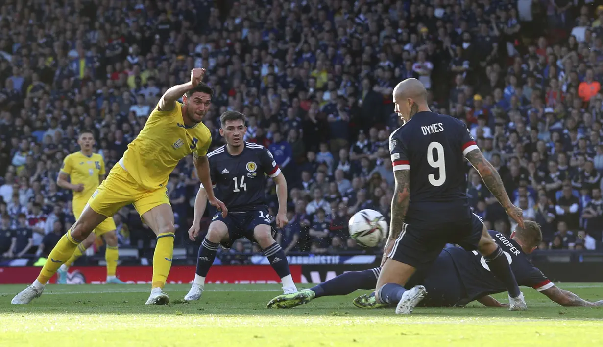 Pemain Skotlandia Lyndon Dykes (kanan) mencoba untuk memblokir tendangan pemain Ukraina Roman Yaremchuk (kiri) pada pertandingan play-off kualifikasi Piala Dunia 2022 di Hampden Park Stadium, Glasgow, Skotlandia, 1 Juni 2022. Ukraina menang 3-1. (AP Photo/Scott Heppell)