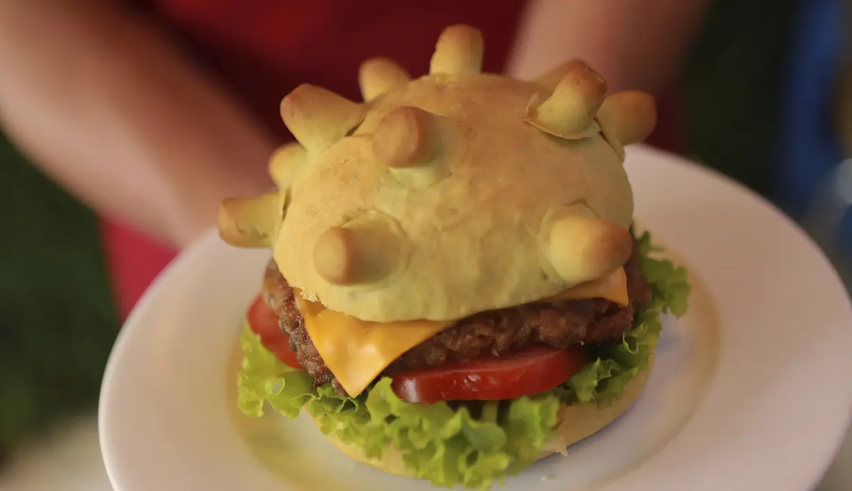 Pemilik restoran Hoang Tung menunjukkan burger berbentuk virus corona COVID-19 di Hanoi, Vietnam, Rabu (25/3/2020). Sebuah restoran di Hanoi membuat kreasi baru mereka yang disebut ‘Burger Corona’. (AP Photo/Hau Dinh)