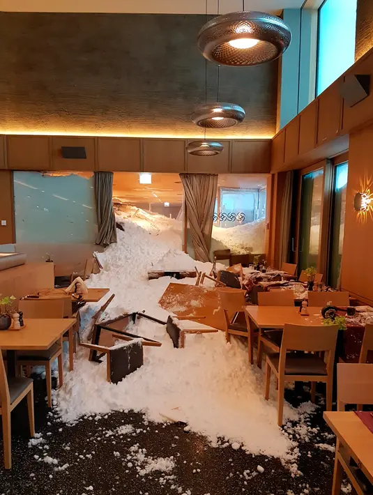Petugas membersihkan longsoran salju yang masuk ke dalam Hotel Saentis di Schwaegalp, Swiss, Jumat (11/1). Badai salju tengah melanda Swiss dan sejumlah negara di Eropa. (Gian Ehrenzeller/Keystone via AP)