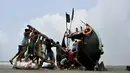 Para nelayan mencoba mengangkat perahu yang terdampar setelah menangkap ikan dari Teluk Benggala di Teknaf, Bangladesh, 28 Maret 2022. (Munir uz Zaman/AFP)