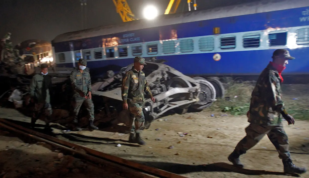 Petugas keamanan setempat saat membantu mengevakuasi korban kecelakaan kereta api yang terjadi di Pukhrayan, Kanpur, India (21/11). Diduga masih banyak korban yang terperangkap di dalam bangkai kereta api. (Reuters/ Jitendra Prakash)