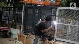 Pekerja melakukan pengelasan saat menyelesaikan pemasangan pagar yang mengelilingi area ruang terbuka hijau (RTH) Tebet Eco Park, Jakarta, Senin (12/12/2022). Pemasangan pagar tersebut membuat taman terkesan lebih rapih dan bagus. (Liputan6.com/Faizal Fanani)