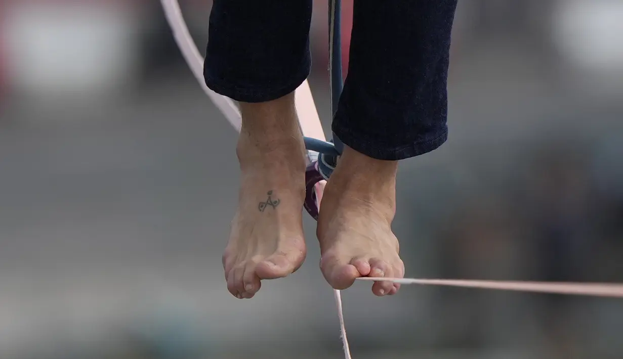 Aksi kedua kalinya akrobatik Nathan Paulin meniti seutas tali slackline yang dipasang pada ketinggian 70 meter antara Menara Eiffel dan Theater Chaillot di Paris, Minggu (19/9/2021). Pada 2019, pria Prancis itu melakukan slackline walk setinggi 150 meter dengan panjang 510 meter. (AP Photo/Francois