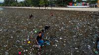 Warga Maratua yang didominasi anak-anak mencari sesuatu di tengah lautan sampah di Pulau Maratua.