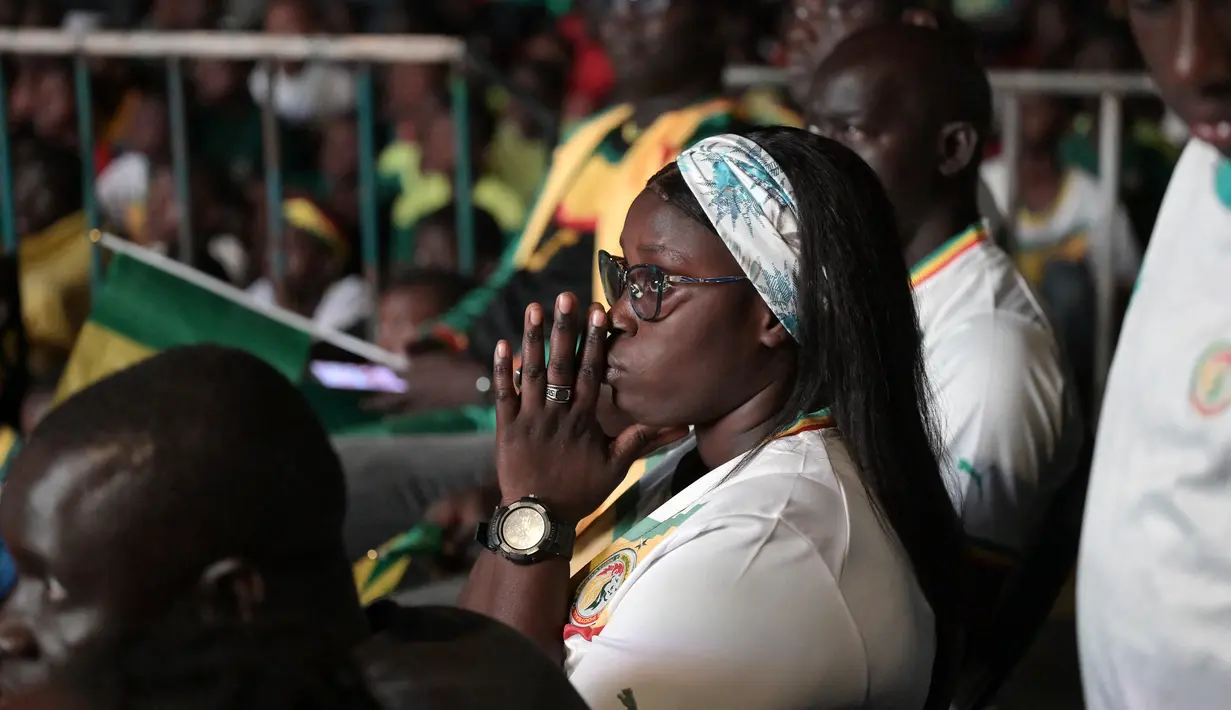 Suporter Senegal bereaksi saat menyaksikan laga babak 16 besar Piala Dunia 2022 saat tim kesayangan mereka melawan Inggris di Qatar, lewat layar video yang dipsang di fan zone di Dakar, Senin (5/12/2022) dini hari WIB. Senegal ditaklukkan Inggris dengan skor 0-3. (Photo by SEYLLOU / AFP)