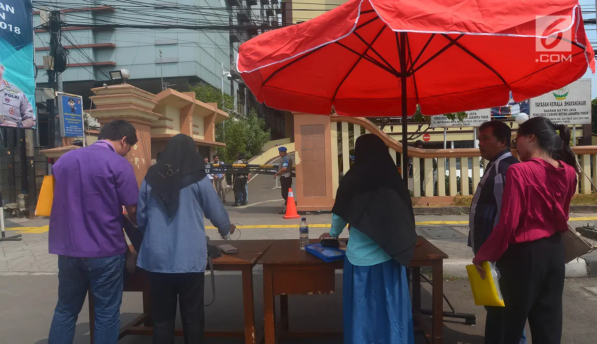 Warga menaruh barang bawaannya sebelum memasuki Polres Jakarta Timur, Rabu (16/5). Sebelumnya telah terjadi serangan dari orang tak dikenal di Mapolda Riau yang menewaskan satu orang polisi pada Rabu (16/5/18) pagi. (Merdeka.com/Imam Buhori)