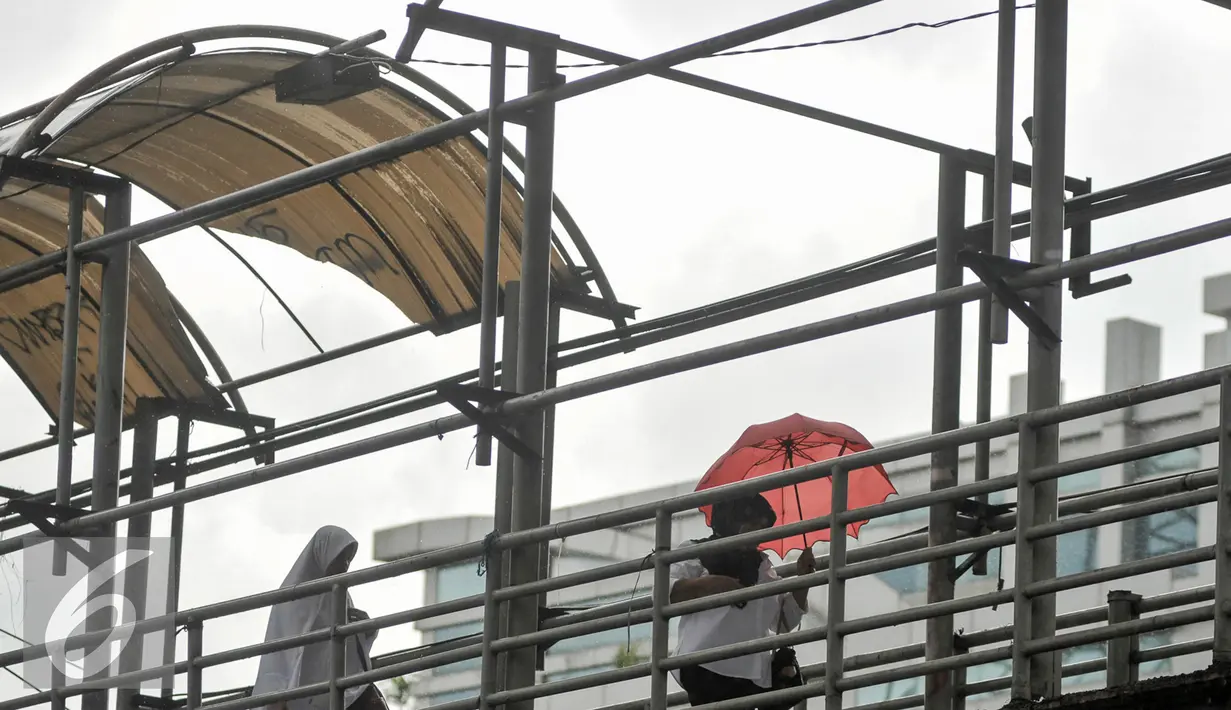 Dua orang wanita melintasi jembatan penyeberangan orang (JPO) di Mampang, Jakarta, Selasa (17/1). Warga berharap pihak berwenang bisa segera memperbaiki JPO demi keamanan dan kenyamanan pengguna. (Liputan6.com/Yoppy Renato)