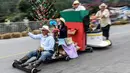 Para peserta menuruni bukit menggunakan kendaraan buatan mereka sendiri dalam festival kendaraan luncur dengan nama Car Festival di Medellin, Kolombia, 17 November 2019. Car Festival ke-30 ini menggunakan gerobak buatan yang dibuat mirip seperti mobil. (JOAQUIN SARMIENTO/AFP)