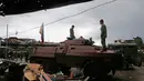 Dua tentara Filipina berdiri diatas tank usai menguasai kota Marawi dari tentara militan, Filipina (17/10). Duterte mendeklarasikan Kota Marawi telah terbebas dari kelompok militan Maute yang berafiliasi dengan ISIS. (AP Photo/Bullit Marquez)