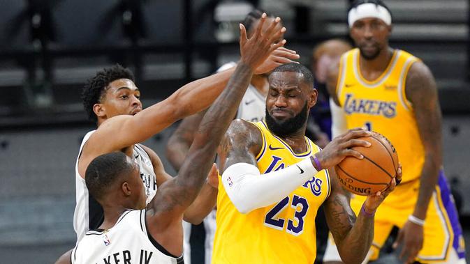 Pebasket Los Angeles Lakers, LeBron James, berebut bola dengan pebasket San Antonio Spurs, Lonnie Walker dan Keldon Johnson pada laga NBA di AT&T Center, Kamis (31/12/2020). LA Lakers menang dengan skor 121-107. (AP/Eric Gay)