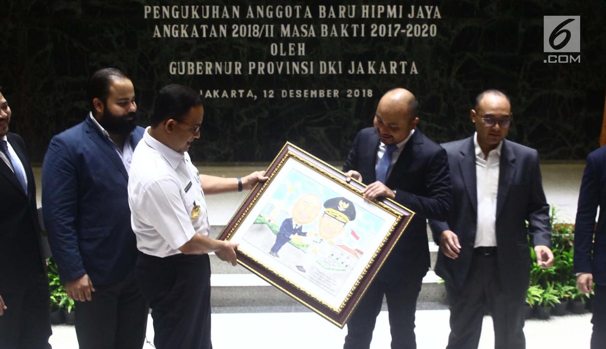 Ketua Umum HIIPMI Jaya Afifuddin Suhaeli Kalla (kanan) menyerahkan cendera mata kepada Gubernur DKI Jakarta Anies Baswedan (kiri) saat pelantikan anggota HIPMI Jaya di Balai Kota Jakarta, Rabu (12/12). (Liputan6.com/Angga Yuniar)