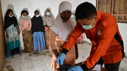 Pengungsi Rohingya mengantre untuk diambil sidik jari untuk menjalani prosedur identifikasi oleh petugas kepolisian di pusat penampungan sementara bekas kantor Imigrasi Punteuet, Aceh Utara (26/6/2020). Mereka menjalani identifikasi dan pemeriksaan tes Covid-19. (AFP Photo/CHAIDEER MAHYUDDIN)