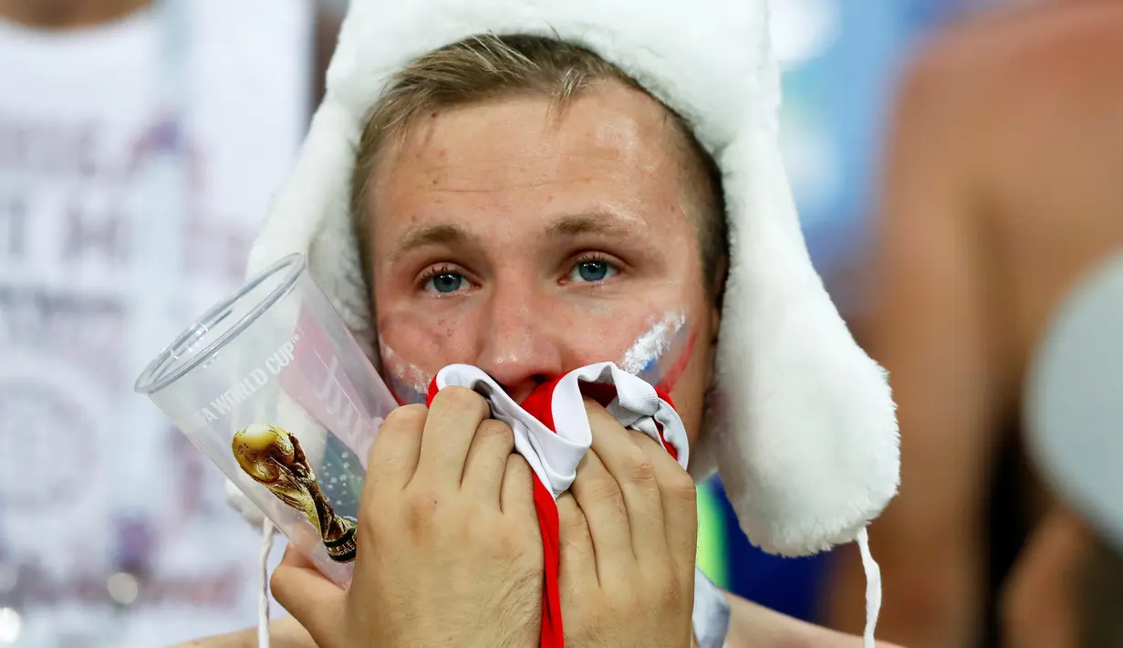 Seorang suporter Rusia terlihat kecewa setelah tim kesayangannya kalah dari Kroasia pada laga perempat final Piala Dunia 2018 di Stadion Olimpiade Fisht, Sabtu (7/7). Tuan rumah Rusia tumbang lewat adu penalti melawan Kroasia 3-4. (AP/Darko Bandic)