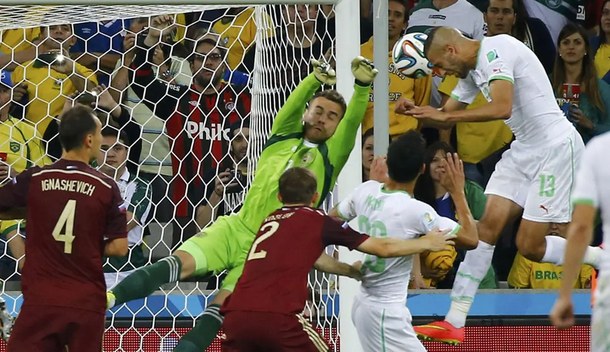 Sundulan kepala pemain depan Aljazair, Islam Slimani (kanan), tidak mampu diredam penjaga gawang Rusia, Igor Akinfeev, di laga penyisihan Piala Dunia Grup H di Stadion Baixada, Curitiba, Brasil, (27/6/2014). (REUTERS/Damir Sagolj)