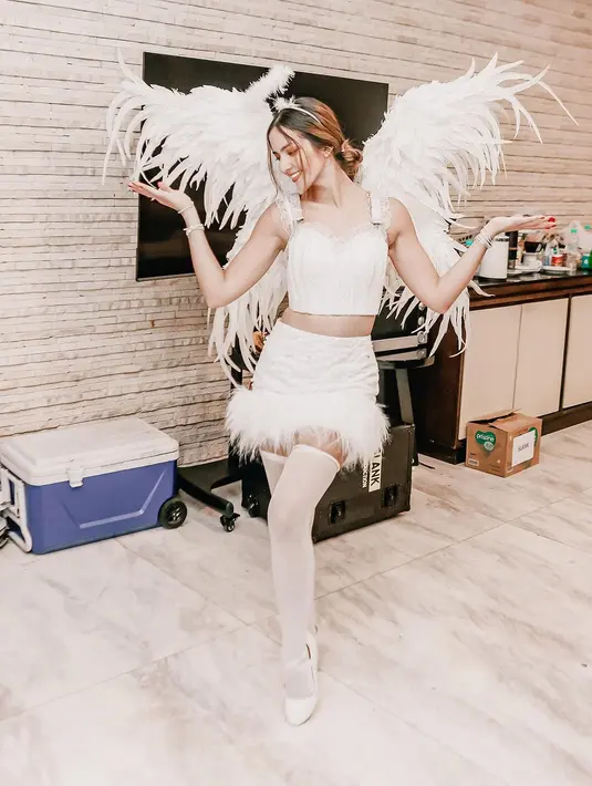 Nia Ramadhani tampil serba putih mengenakan kostum bidadari. Ia memadukan bustier dan rok mini berbulu warna putih. Lengkap dengan sayap dan mahkota awan khas bidadari [@ramadhaniabakrie]
