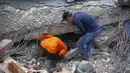 Tim penyelamat mencari korban di antara reruntuhan bangunan yang rusak akibat gempa bumi di Mamuju, Sulawesi Barat, Jumat (15/1/2021). Setidaknya 34 orang meninggal dunia akibat gempa dahsyat tersebut. (AP/Yusuf Wahil)