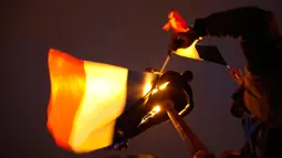 Seorang pria memanjat lampu jalan sambil membawa bendera Prancis di luar museum Louvre, Paris, Minggu (7/5). Ratusan pendukung Emmanuel Macron menyambut kemenangan kandidat termuda yang terpilih sebagai presiden negeri itu . (AP Photo/Laurent Cipriani)