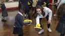 Duchess of Cambridge, Kate Middleton bermain dengan salah satu anak saat mengunjungi Bond Primary School di Mitcham, London, 17 Januari 2018. Meski perutnya sudah semakin besar, istri Pangeran William tersebut tetap saja lincah. (Arthur Edwards /POOL/AFP)