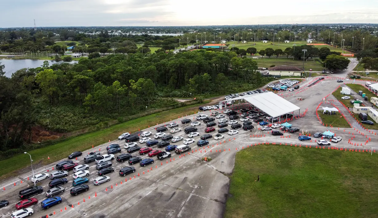 Pandangan udara menunjukkan mobil berbaris di lokasi pengujian Covid-19 di Tropical Park di Miami, Florida, Selasa (21/12/2021). Beberapa hari sebelum Natal, orang Amerika menghadapi antrean panjang untuk dites covid-19 di tengah lonjakan baru yang didorong oleh varian Omicron. (CHANDAN KHANNA/AFP)