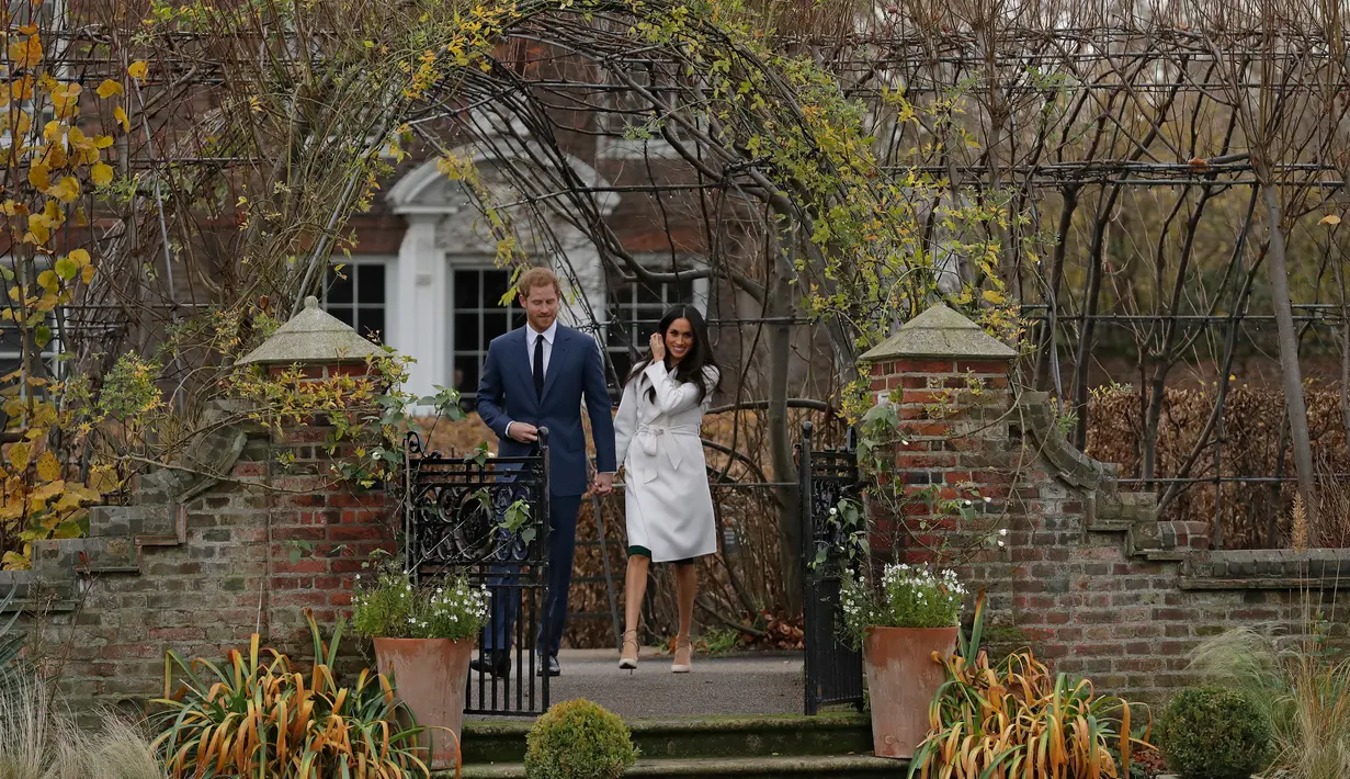 Pangeran Harry dan aktris AS, Meghan Markle berjalan untuk mengumumkan pertunangan mereka kepada media di Kensington Palace, London, Senin (27/11). Pangeran Harry dan Meghan Markle bertunangan di London pada awal November ini. (AP/Matt Dunham)