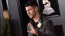 Penyanyi Nick Jonas menyematkan mawar putih pada jasnya ketika berjalan di karpet merah Grammy Awards 2018, New York, Minggu (28/1). Mereka memilih warna putih untuk mendukung MeToo, gerakan melawan pelecehan seksual. (Evan Agostini/Invision/AP)