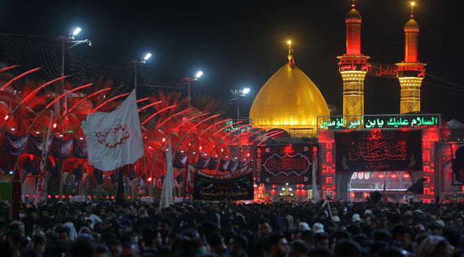 Umat ​​Muslim Syiah berdoa di luar tempat suci Imam Hussein (latar belakang) saat peringatan bulan Muharram di Karbala, Irak, Kamis (19/8/2021). Muharram adalah bulan berkabung bagi kaum Syiah untuk memperingati kematian cucu Nabi Muhammad, Imam Hussein. (AP Photo/Anmar Khalil)