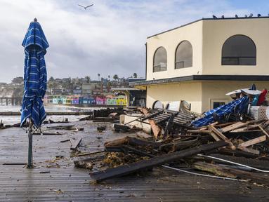 Puing-puing badai didorong ke atas Tacos Morenos di Capitola, California, Kamis (5/1/2023). Angin topan yang merusak, ombak bergelombang dan hujan lebat dari "sungai atmosfer" yang kuat menghantam California pada hari Kamis, melumpuhkan listrik hingga puluhan ribu, menyebabkan banjir, dan mengakibatkan kematian setidaknya dua orang, termasuk seorang anak yang rumahnya dihantam pohon tumbang. (AP Photo/Nic Coury)