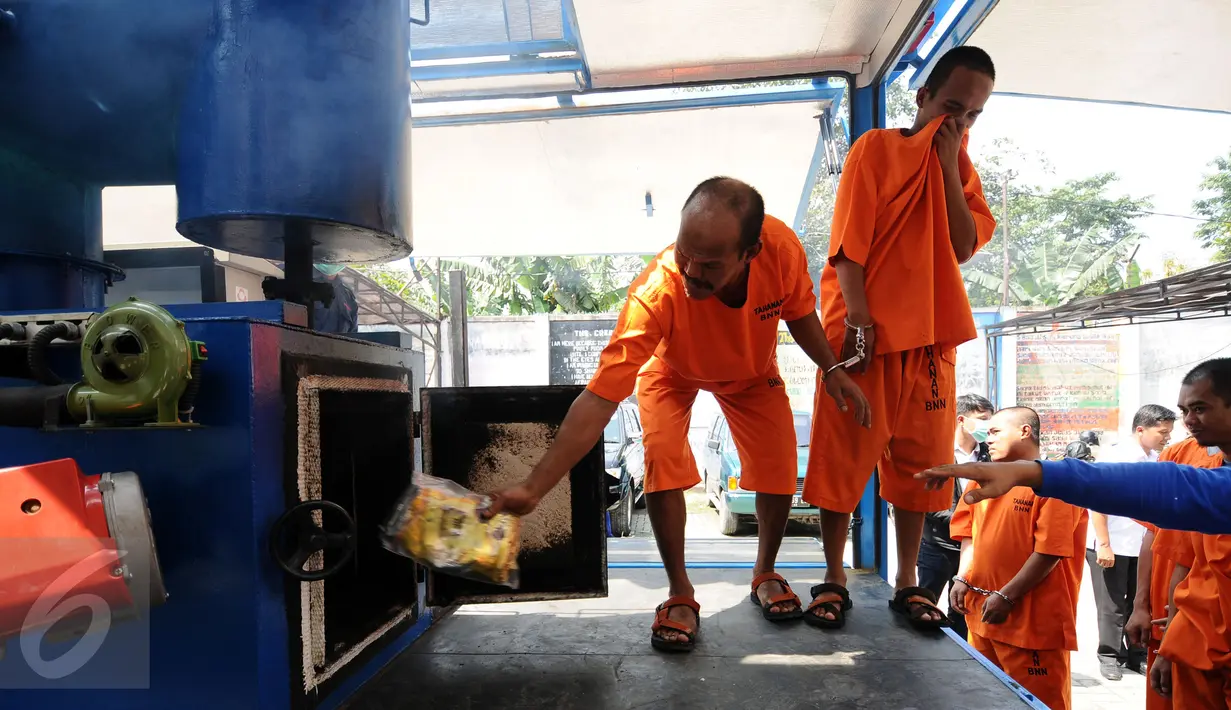 Salah satu tersangka memasukkan barang bukti ke dalam mesin pemusnah narkotika di halaman kantor BNN, Jakarta, Kamis (9/3). Narkotika yang dimusnahkan jenis sabu 40,57 kilogram dan 44.3787 butir pil ekstasi. (Liputan6.com/Helmi Fithriansyah)