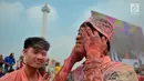 Warga memegangi wajahnya yang penuh dengan serbuk warna saat colour run dalam Festival Damai di Monas, Jakarta, Minggu (23/6/2019). Serbuk warna-warni yang ditembakkan oleh meriam menambah kemeriahan Festival Damai. (merdeka.com/Iqbal Nugroho)