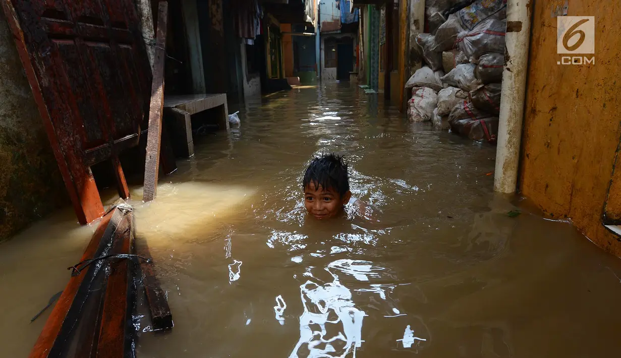 Seorang anak bermain saat banjir merendam permukiman di Kebon Pala, Jatinegara, Jakarta, Selasa (26/2/2019). Banjir karena Sungai Ciliwung meluap akibat air kiriman dari Bogor itu menyebabkan aktivitas warga terganggu. (Merdeka.com/Imam Buhori)