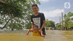 Warga melintasi banjir di Desa Sukalaksana Kabupaten Bekasi, Jawa Barat, Senin (22/02/2021). Jebolnya tanggul Sungai Citarum ini disebabkan oleh debit air yang tinggi. (Liputan6.com/Herman Zakharia)