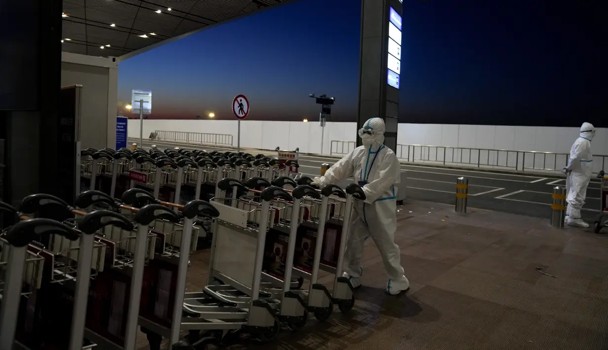Seorang pekerja Olimpiade mengenakan pakaian pelindung mendorong troli di bandara Internasional Ibu Kota Beijing setelah Olimpiade Musim Dingin 2022, di Beijing, China, Senin (21/2/2022). (AP Photo/Natacha Pisarenko)