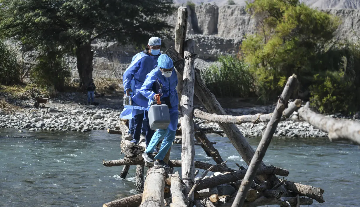 Petugas kesehatan menyeberangi Sungai Camana untuk vaksinasi Covid-19 kepada warga lanjut usia di desa pedalaman di Arequipa, Peru (2/7/2021). Peru menggencarkan vaksinasi warga lanjut usia dengan vaksin Pfizer-BioNTech sebagai upaya untuk mengatasi pencegahan pandemi Covid-19. (AFP/Diego Ramos)