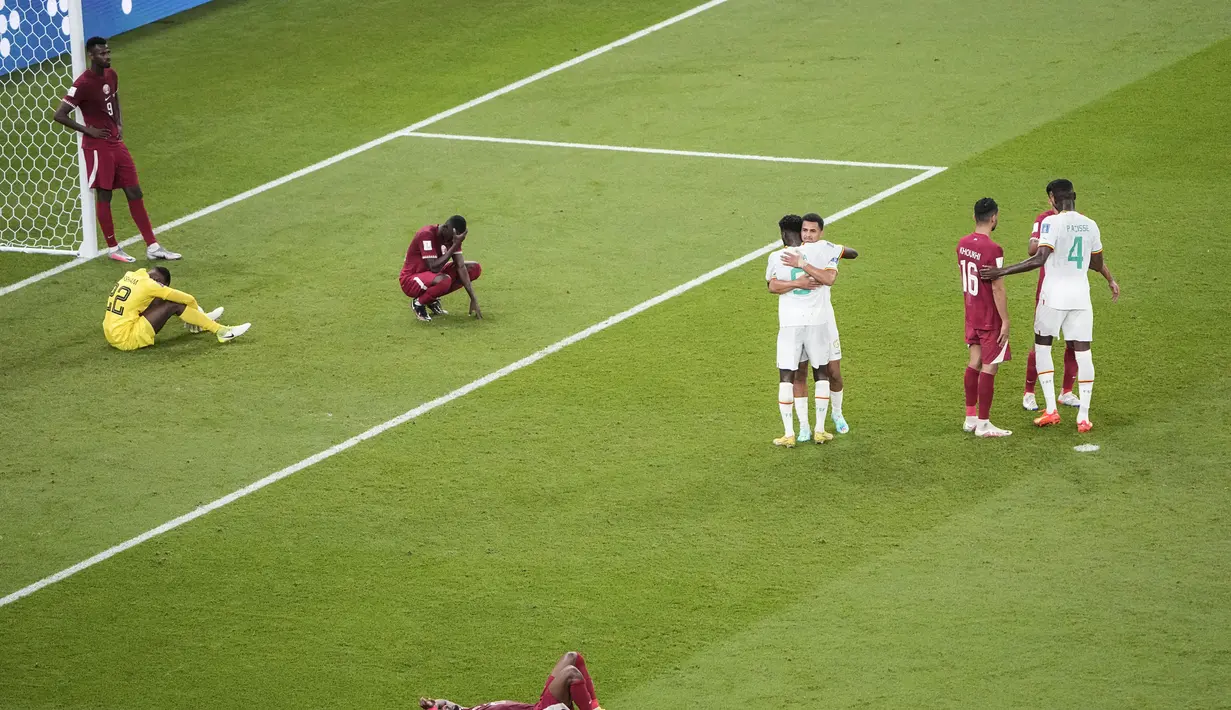 Para pemain Qatar melihat pemain Senegal merayakan kemenangan 3-1 setelah pertandingan grup A Piala Dunia antara Qatar dan Senegal, di Stadion Al Thumama di Doha, Qatar, Jumat, 25 November 2022. Capaian maksimal Qatar adalah merebut tiga angka yang diraih pada duel pamungkas kontra Belanda, Selasa (29/11/2022). Sedangkan Belanda dan Ekuador sudah memiliki empat poin. (AP Photo/Ariel Schalit)