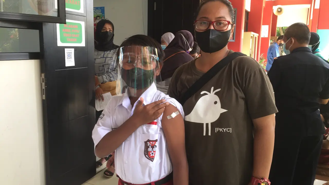 Gevyn Nhurberthus, salah satu murid SDN Kalibata 11 Jakarta Selatan, bersama orangtuanya usai mendapat vaksin Covid-19