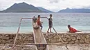 Anak-anak bersantai sejenak ditepi pantai sebelum bermain sepak bola di Alor, Nusa Tenggara Timur. (Bola.com/Nicklas Hanoatubun)