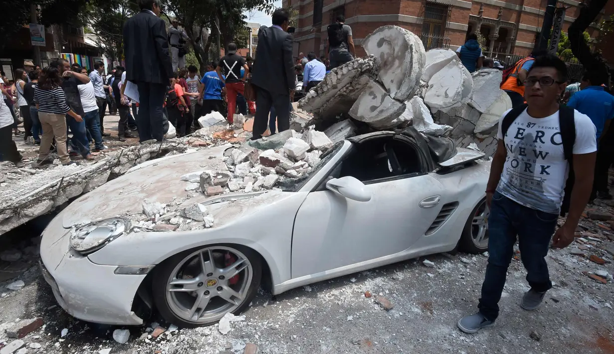 Sebuah mobil yang hancur tertimpa bangunan setelah gempa mengguncang Kota Meksiko (19/9). Gempa berkekuatan 7,1 Skala Richter mengguncang Ibu Kota Mexico City. (AFP Photo/Alfredo Estrella)