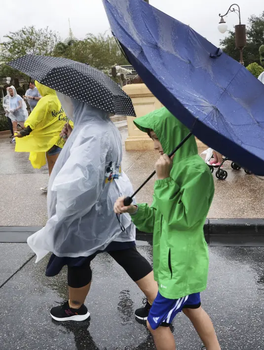 Angin meniup payung pengunjung saat meninggalkan Walt Disney World karena kondisi memburuk saat mendekatnya Badai Nicole di Danau Buena Vista, Florida, Rabu (9/11/2022). Semua taman Disney di Florida Tengah ditutup Rabu pagi karena badai yang akan datang. (Joe Burbank/Orlando Sentinel via AP)