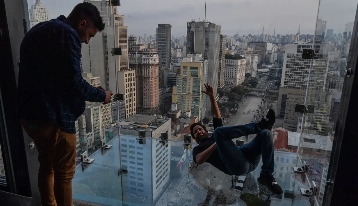 Seorang pengunjung berpose di Sampa Sky Observation Deck di Sao Paulo, Brasil pada 05 Agustus 2021. Gedung tersebut terinspirasi dari Skydeck Chicago di Amerika Serikat yang memiliki tinggi 103 lantai. (NELSON ALMEIDA / AFP)