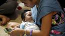 Seorang ibu menyusui anaknya sambil bermain ponsel di kota Mandaluyong, Filipina, Sabtu (1/8/2015). Dalam rangka memperingati Hari ASI Sedunia, mereka menggelar kegiatan menyusui yang disebut "Hakab Na 2015".  (REUTERS/Susan Corpuz)