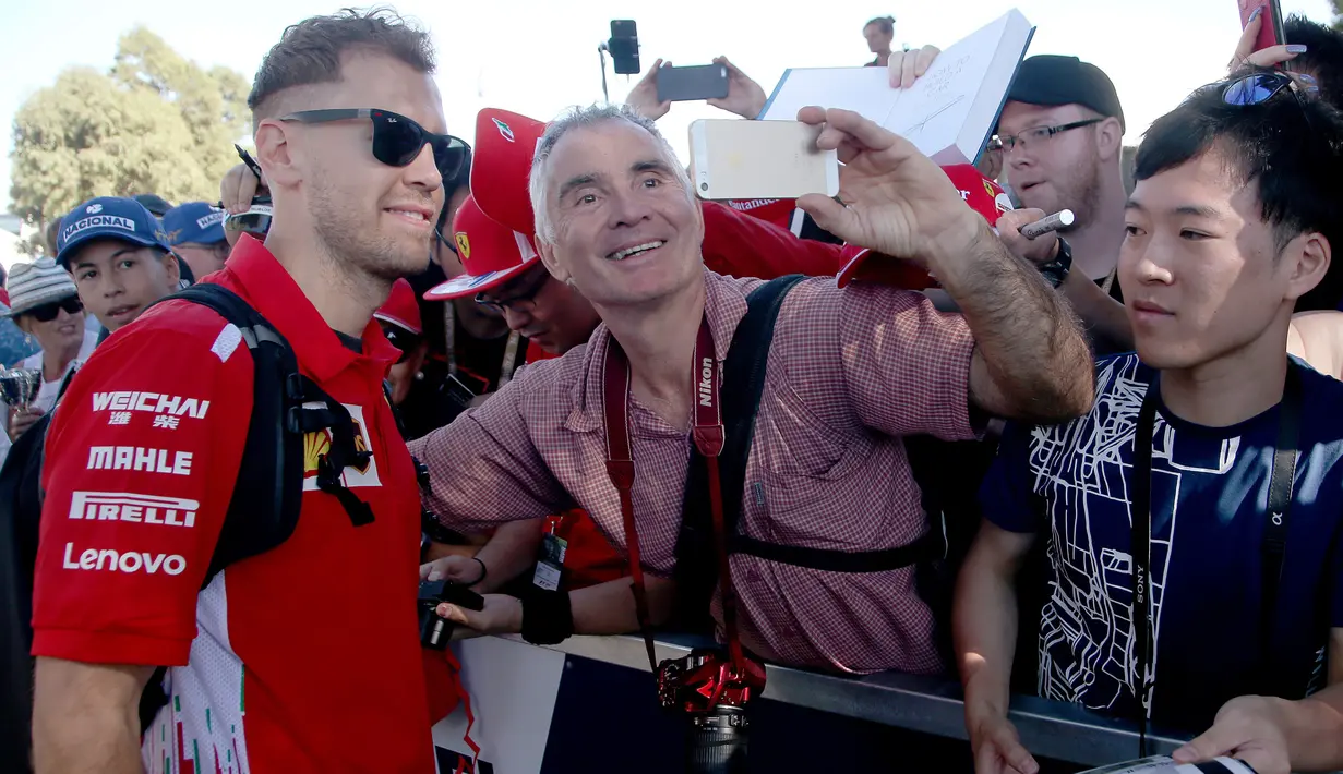 Pembalap tim Ferrari, Sebastian Vettel berswafoto dengan fans sesaat sebelum latihan bebas Formula 1 (F1) GP Australia di Melbourne, Jumat (23/3). Balapan F1 GP Australia 2018 sendiri akan bergulir pada Minggu, 25 Maret besok. (AP/Rick Rycroft)