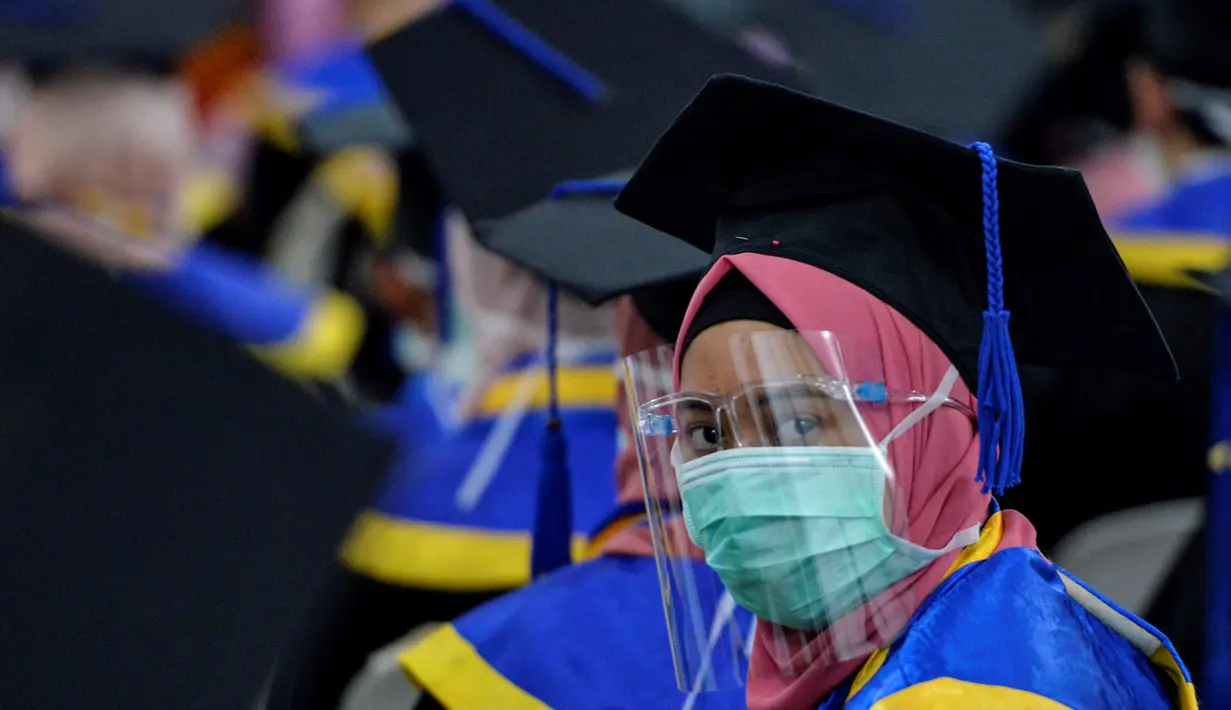 Seorang siswa yang mengenakan masker dan pelindung sebagai tindakan pencegahan terhadap virus Corona COVID-19 mengikuti acara wisuda SMK Farmasi di Banda Aceh (24/9/2020). (AFP/Chaideer Mahyuddin)