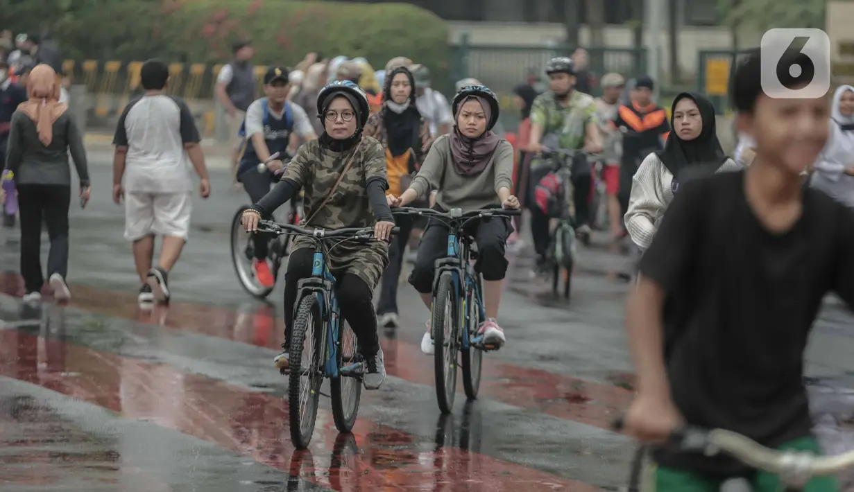 Warga bersepeda saat car free day (CFD) di kawasan Bundaran HI, Jakarta, Minggu (29/12/2019). Kendati tidak seramai saat cerah, warga yang berlari, jalan santai, atau swafoto masih menjadi pemandangan di area CFD usai hujan mengguyur Jakarta. (Liputan6.com/Faizal Fanani)