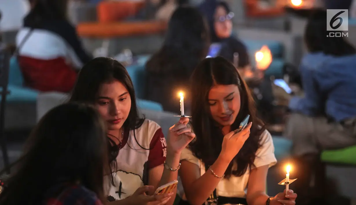 Pengunjung menyalakan lilin mendukung Earth Hour 2019 di Lippo Mall Kemang, Jakarta, Sabtu (30/3). Sebanyak 70 mal yang dikelola Lippo Malls Indonesia serentak memadamkan lampu eksterior dan 50% lampu penerangan di dalam gedung dari pukul 20:30 - 21:30 waktu setempat. (Liputan6.com/Fery Pradolo)