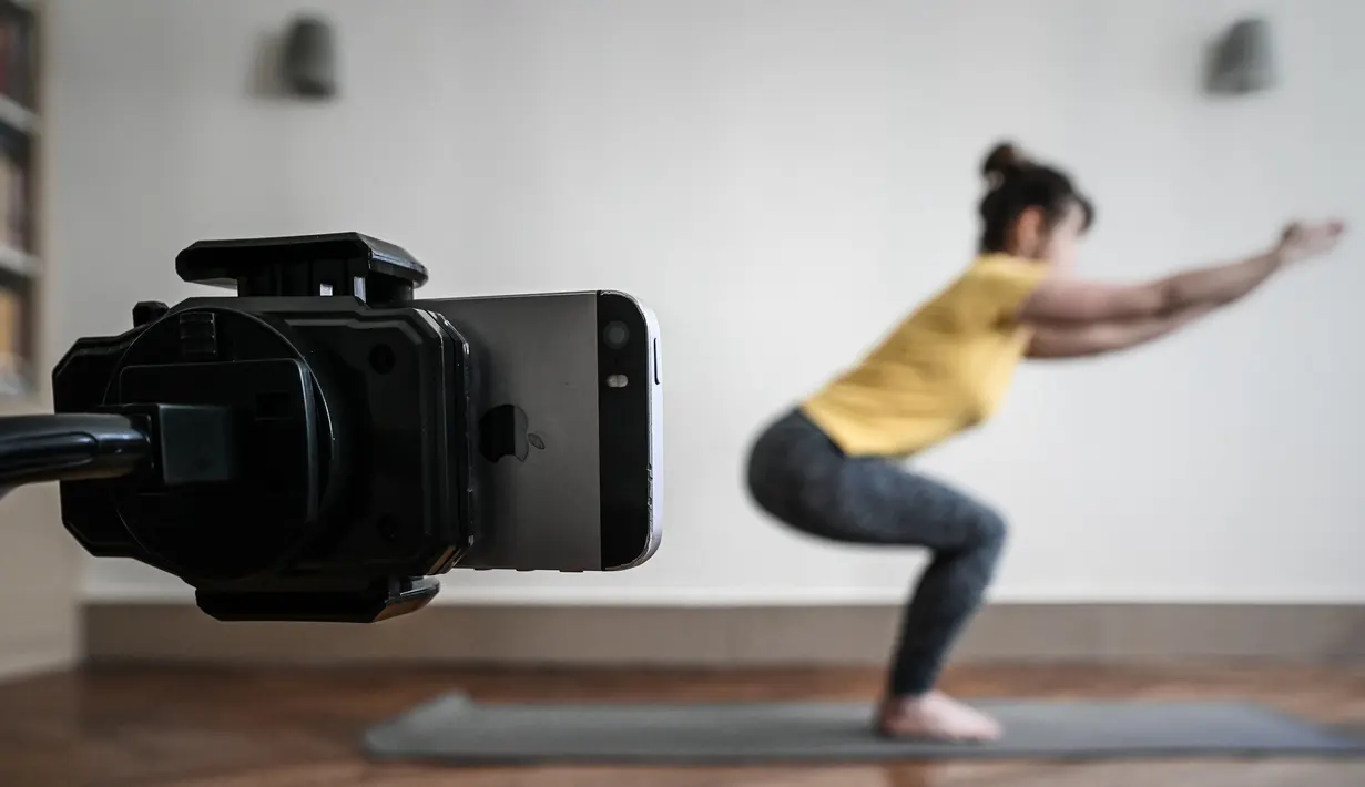 Seorang guru yoga berlatih sebelum mengajar kelas live di akun Instagram-nya pada hari kesembilan belas selama lockdown yang bertujuan untuk membatasi penyebaran infeksi COVID-19 yang disebabkan oleh coronavirus novel di Paris, Prancis (4/4/2020). (AFP/Philippe Lopez)