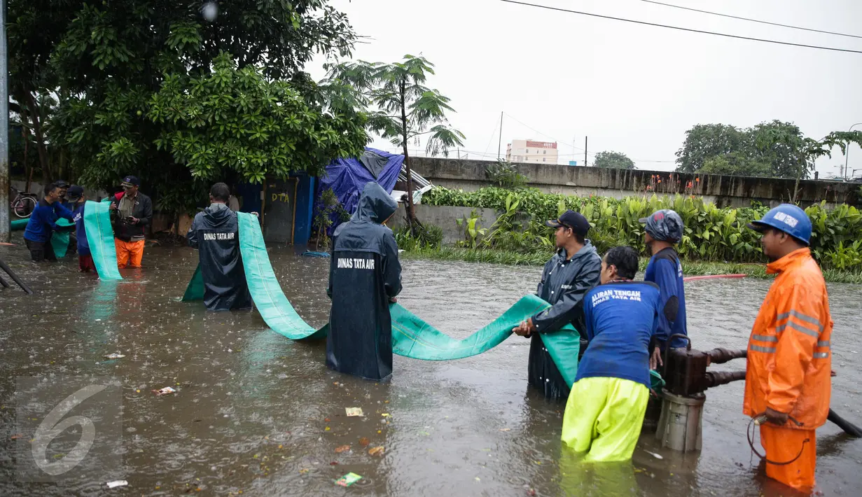 Petugas Suku Dinas Tata Air menarik selang pembuangan saat melakukan penyedotan air banjir di Jalan Gunung Sahari, Jakarta, Selasa (21/2). Hujan yang mengguyur sejak Selasa dinihari membuat sebagian wilayah di Jakarta banjir. (Liputan6.com/Faizal Fanani)